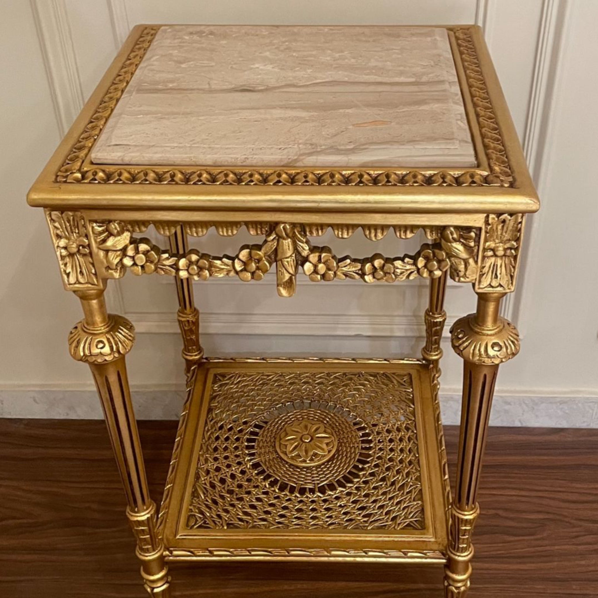 ترابيزة ركن فاخرة بزخارف نحاسية وقرصة رخام - طاولة ركن أنيقة بتصميم كلاسيكي مميز مصنوعة من خشب الزان المتين، مطلية بلون ذهبي فاخر مع زخارف يدوية تضيف لمسة فخامة. القرصة من الرخام الطبيعي، والرف السفلي يتميز بتصميم شبكي مزخرف فني يعزز جمالها ويضيف طابعًا تراثيًا ساحرًا الخاماتالهيكل: خشب زان طبيعيالسطح: رخام طبيعيالرف السفلي: إطار مزخرف بلون ذهبي المقاساتالعرض: 46 سمالارتفاع: 73 سمالعمق: 46 سم
