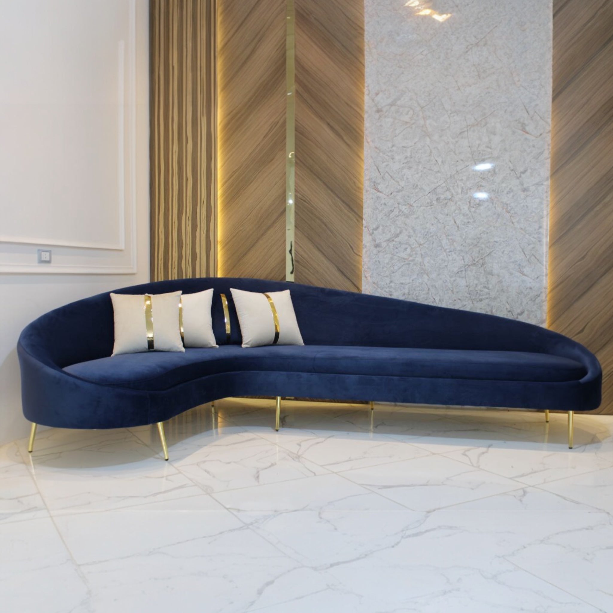 ركنة هلال - ركنة هلال الشكل والتصميم: تصميم هلالي أنيق يُضفي لمسة عصرية على أي مساحة. القاعدة مزودة بأرجل معدنية ذهبية لامعة تضيف لمسة من الفخامة. الوسائد مزينة بشرائط ذهبية تضفي جمالاً متناغماً مع التصميم العام. القماش: نوع القماش: جيرمان. يتميز بملمسه الناعم ومتانته العالية. متوفر بألوان متنوعة تناسب جميع الأذواق والديكورات. المزايا: تصميم مناسب للمساحات العصرية. مريح للاسترخاء ويُضفي لمسة راقية على الغرفة. يمكن استخدامه في غرف المعيشة أو الاستقبال. الأبعاد: الطول الكلي: 3 متر. العرض الكلي: 2 متر.