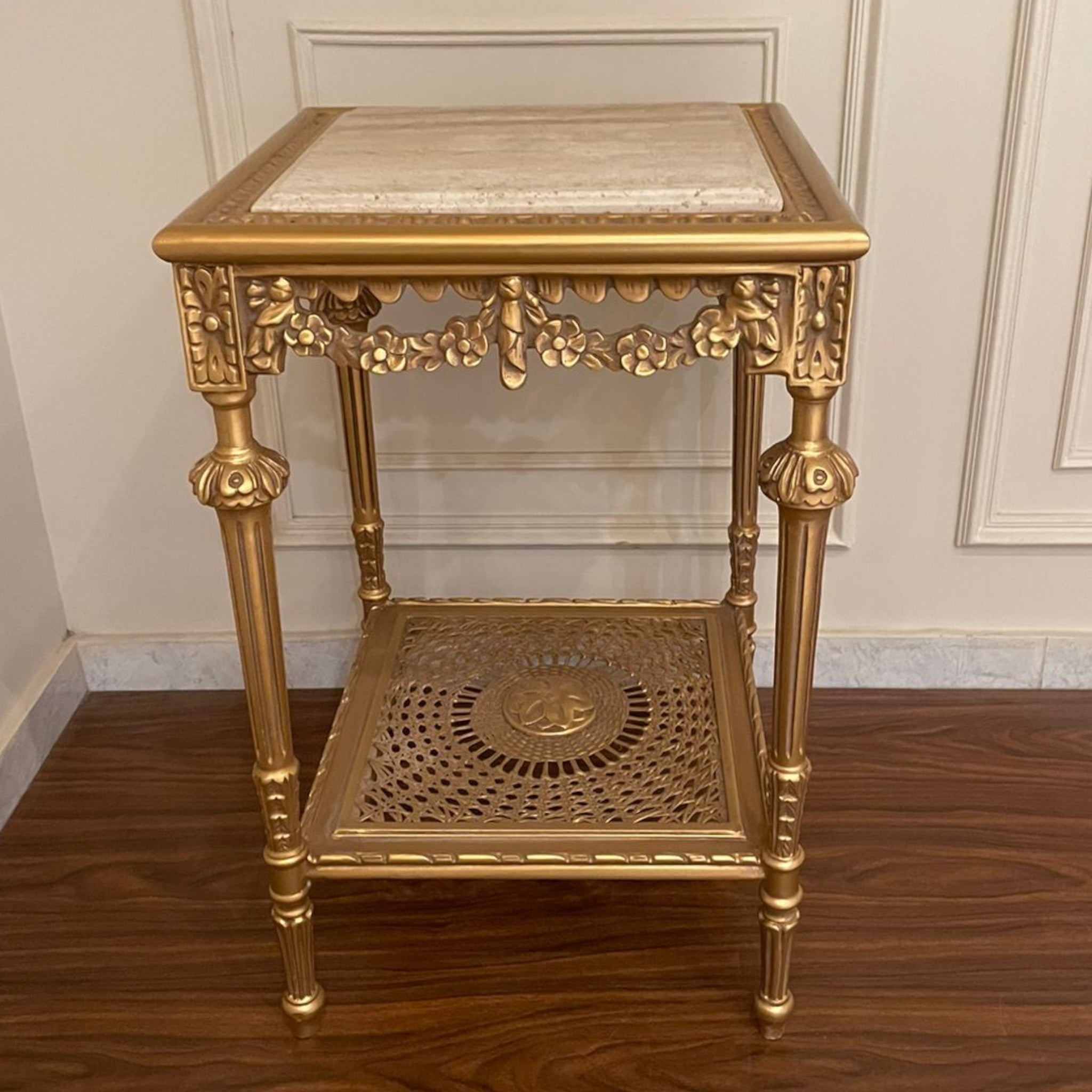 ترابيزة ركن فاخرة بزخارف نحاسية وقرصة رخام - طاولة ركن أنيقة بتصميم كلاسيكي مميز مصنوعة من خشب الزان المتين، مطلية بلون ذهبي فاخر مع زخارف يدوية تضيف لمسة فخامة. القرصة من الرخام الطبيعي، والرف السفلي يتميز بتصميم شبكي مزخرف فني يعزز جمالها ويضيف طابعًا تراثيًا ساحرًا الخاماتالهيكل: خشب زان طبيعيالسطح: رخام طبيعيالرف السفلي: إطار مزخرف بلون ذهبي المقاساتالعرض: 46 سمالارتفاع: 73 سمالعمق: 46 سم
